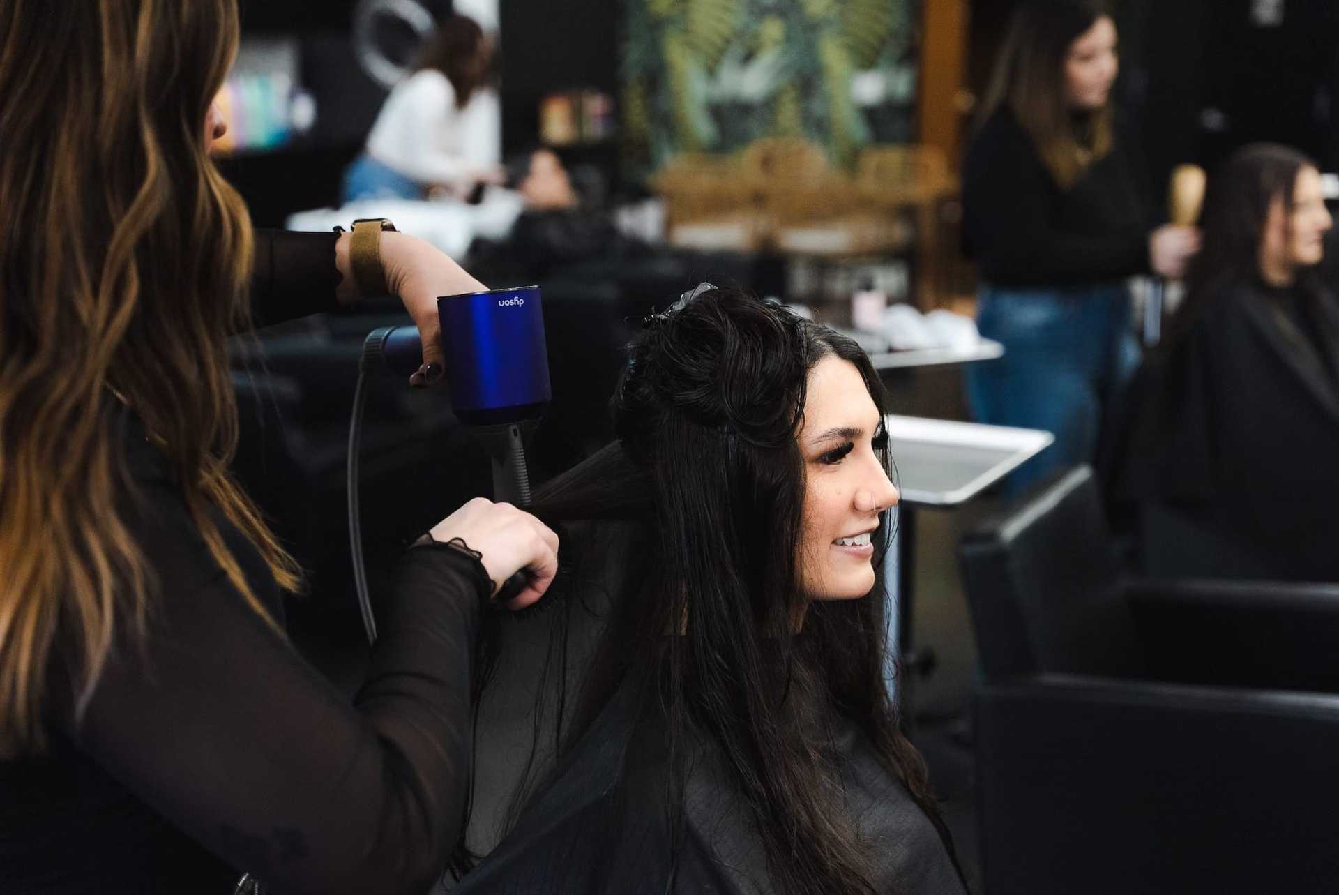 Woman getting hair styled with blow dryer in a salon.
