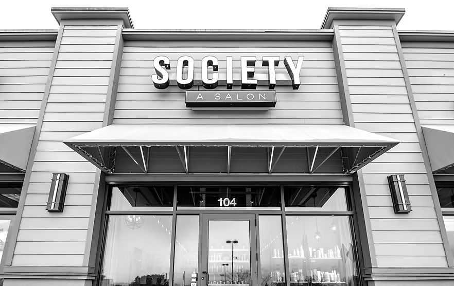Front view of Society salon with glass door and large signage.