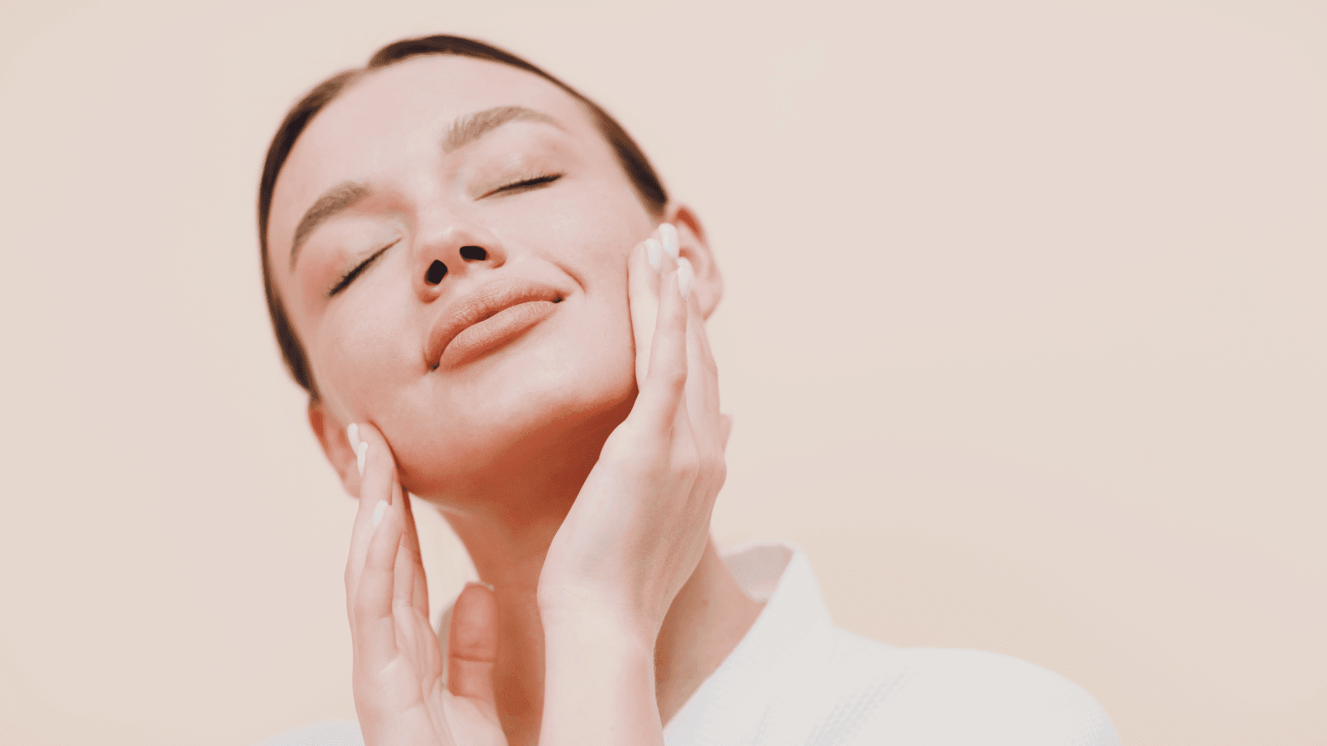 Woman gently touching her face with closed eyes, expressing relaxation and skincare.